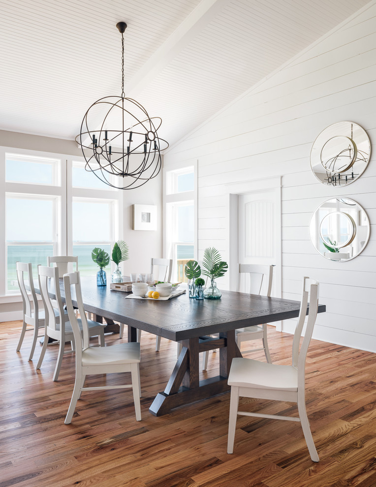 Foto di una grande sala da pranzo aperta verso il soggiorno costiera con pareti bianche, pavimento in legno massello medio e pavimento marrone