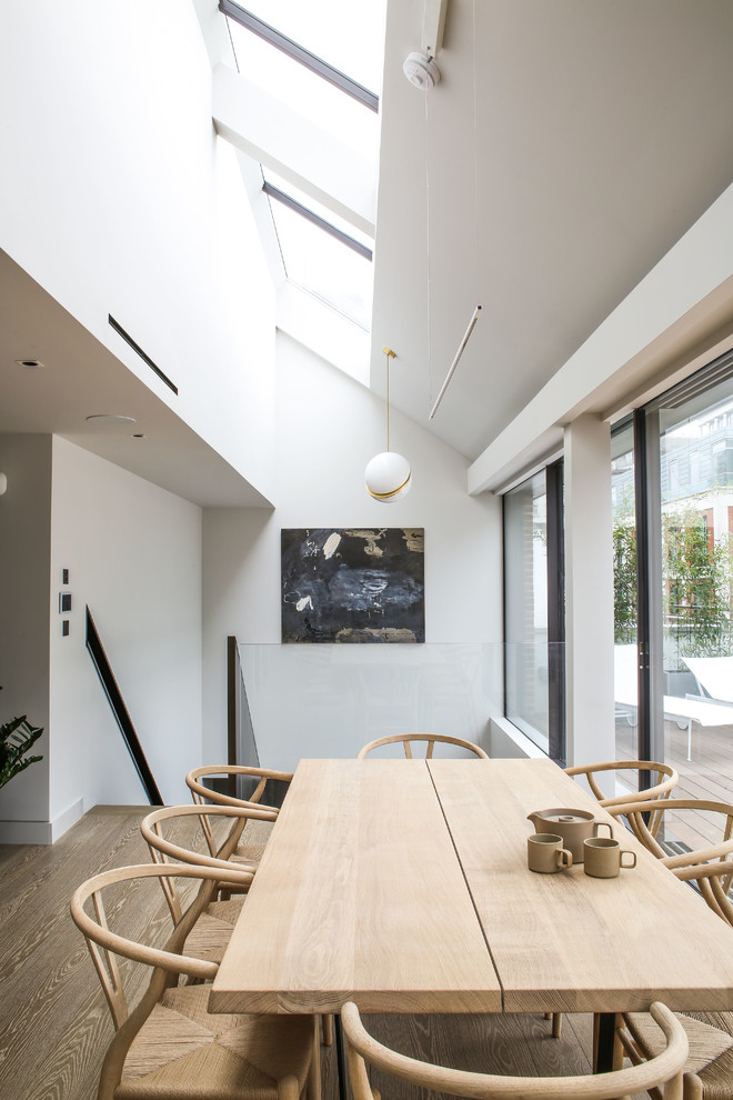 Offenes, Großes Modernes Esszimmer ohne Kamin mit weißer Wandfarbe und hellem Holzboden in London