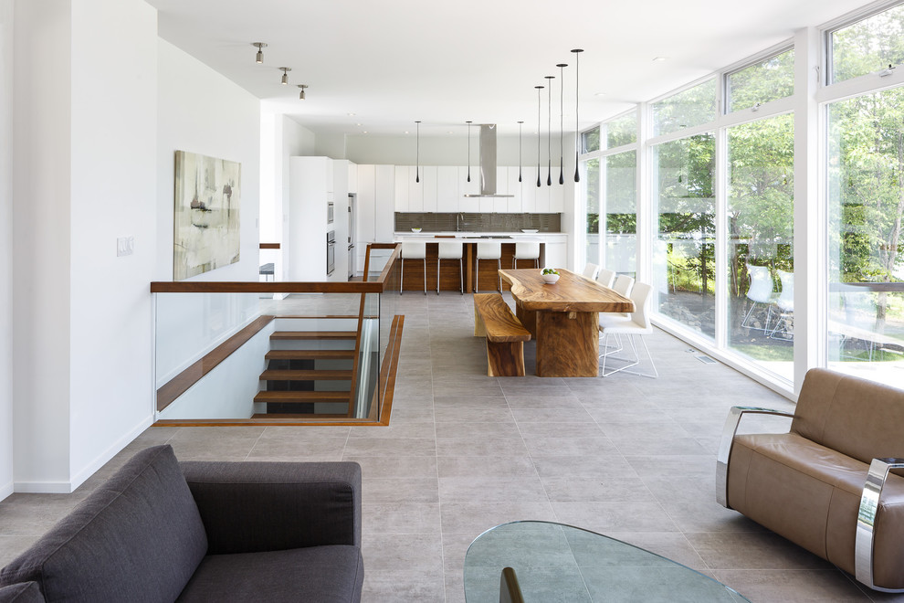 Immagine di una sala da pranzo aperta verso il soggiorno minimalista con pareti bianche e pavimento in cemento