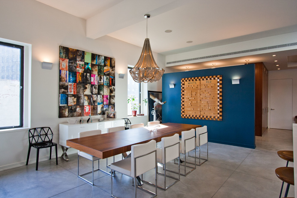 Cette photo montre une salle à manger ouverte sur le salon tendance avec un mur blanc et sol en béton ciré.