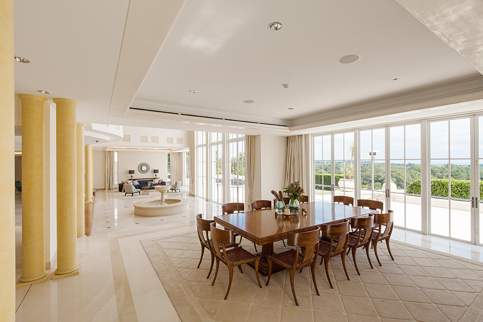 Cette image montre une très grande salle à manger ouverte sur le salon design avec un mur beige, un sol en marbre et un sol beige.