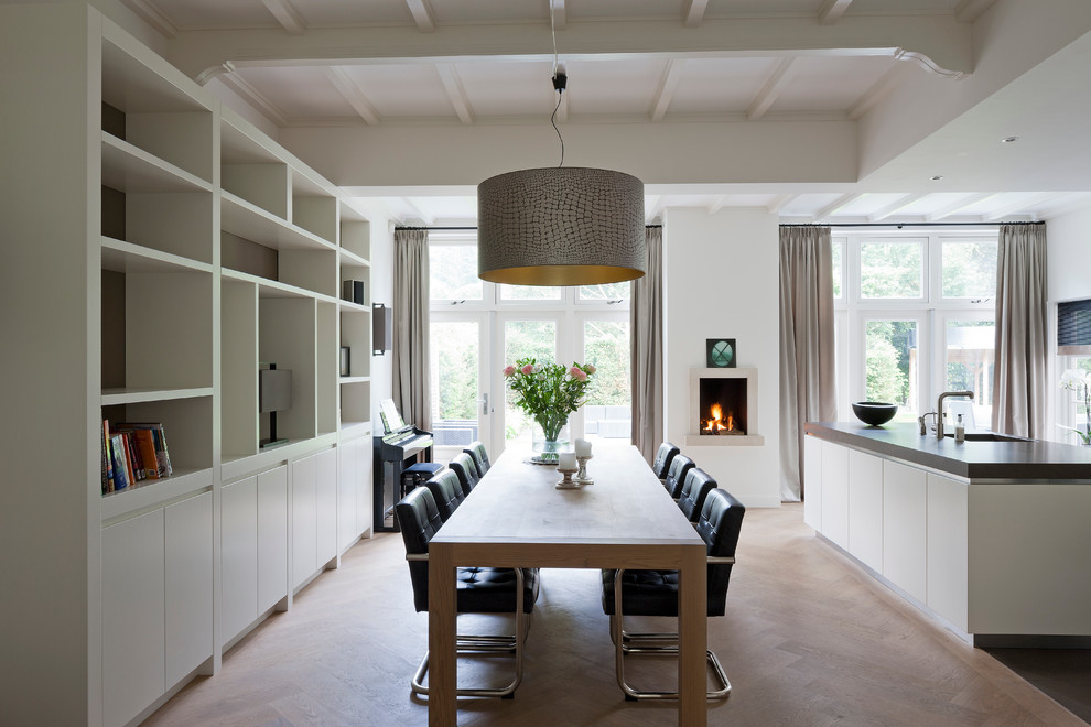 Esempio di una sala da pranzo aperta verso la cucina design con pareti gialle, pavimento in legno massello medio e camino classico