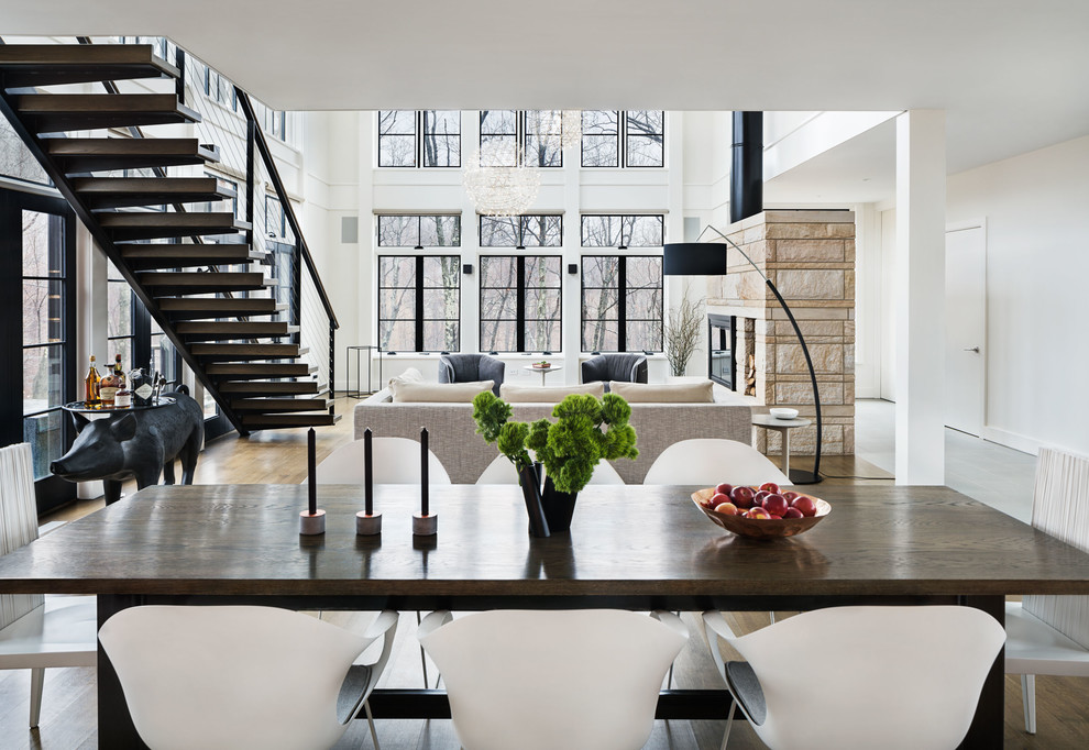 Cette image montre une salle à manger minimaliste avec un sol en bois brun et un manteau de cheminée en pierre.