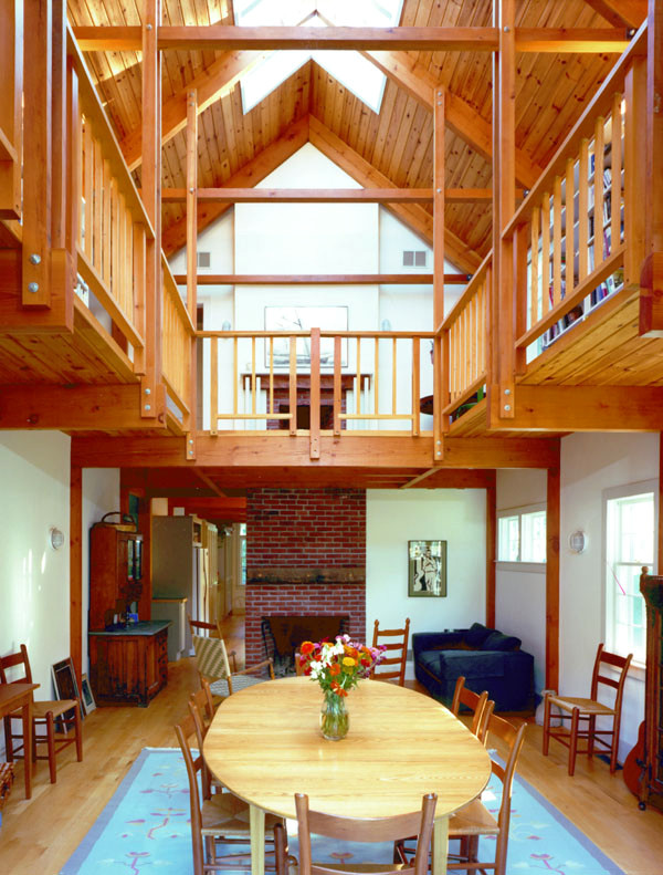 Réalisation d'une salle à manger ouverte sur la cuisine champêtre de taille moyenne avec un mur blanc, un sol en bois brun, une cheminée standard et un manteau de cheminée en brique.