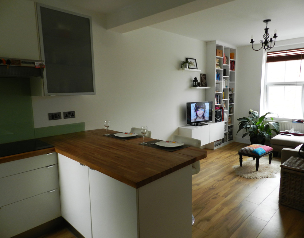 Cette image montre une petite salle à manger ouverte sur la cuisine design avec un mur blanc et un sol en bois brun.