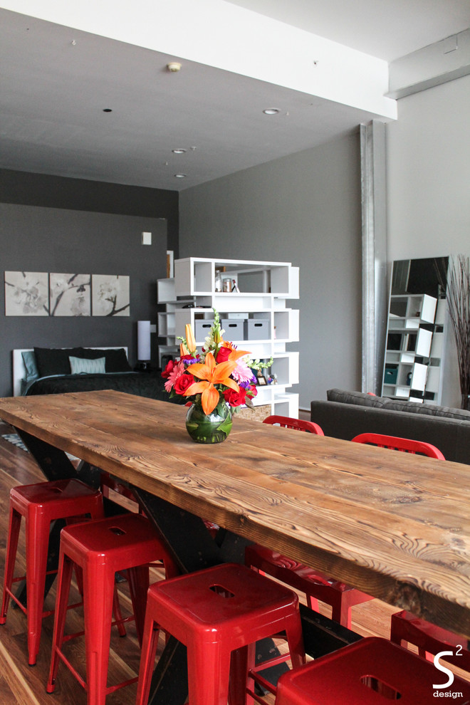 Ejemplo de comedor industrial abierto con paredes grises y suelo de madera en tonos medios