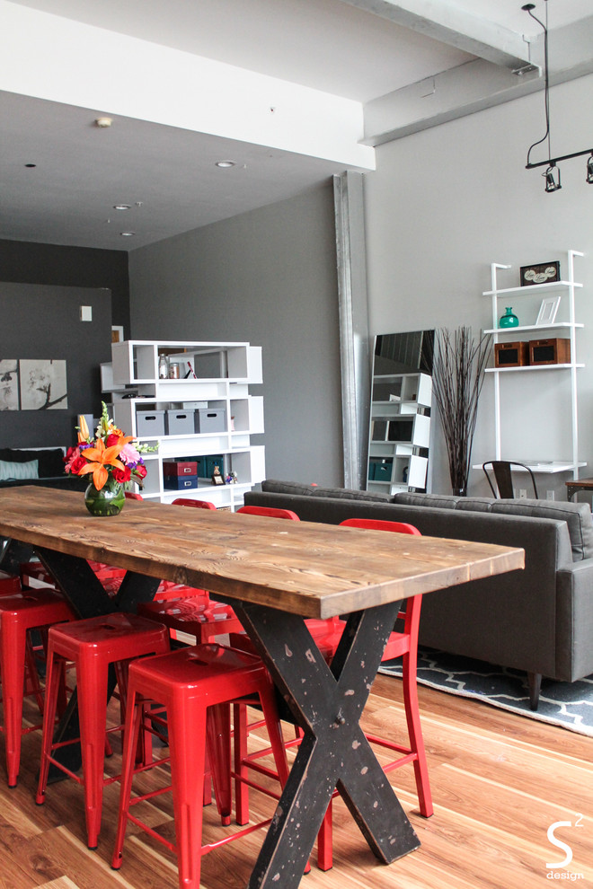 Idée de décoration pour une salle à manger ouverte sur le salon urbaine avec un mur gris et un sol en bois brun.
