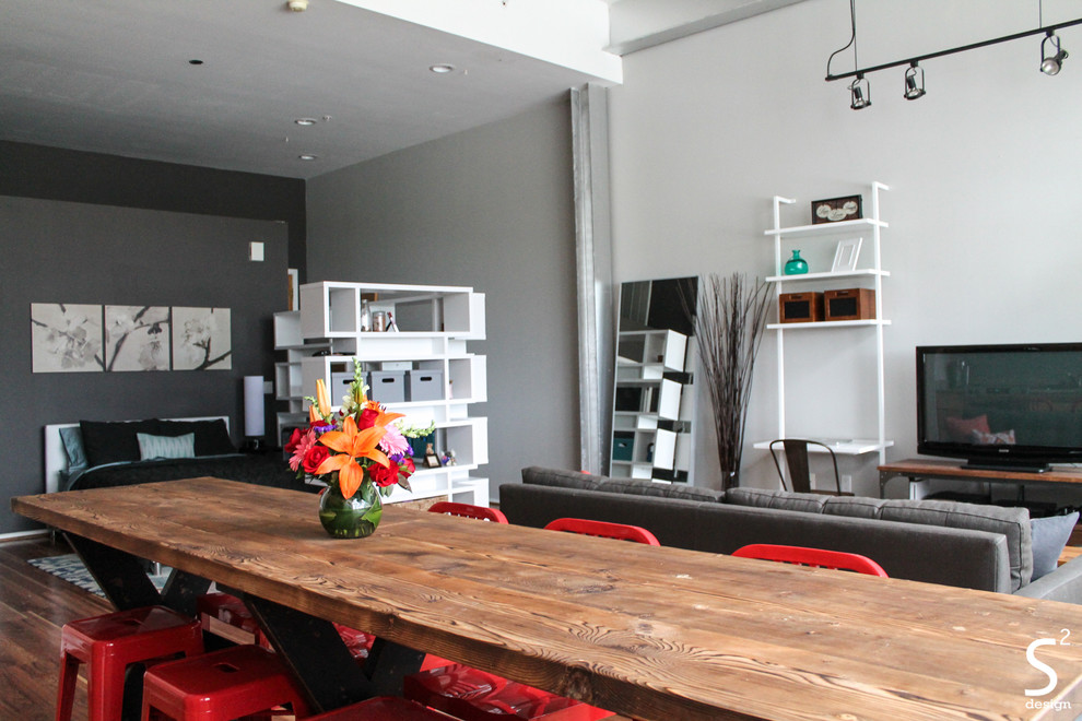 Photo of an industrial open plan dining room in Houston with grey walls and medium hardwood flooring.