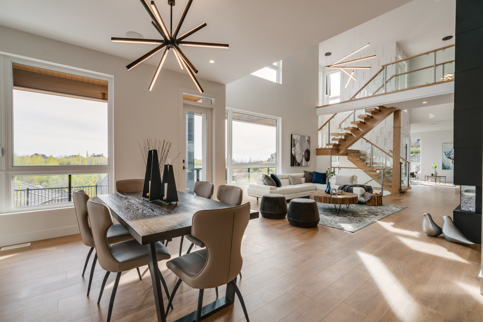 Immagine di una grande sala da pranzo contemporanea con pareti bianche, pavimento in laminato, camino bifacciale, cornice del camino in perlinato e pavimento marrone