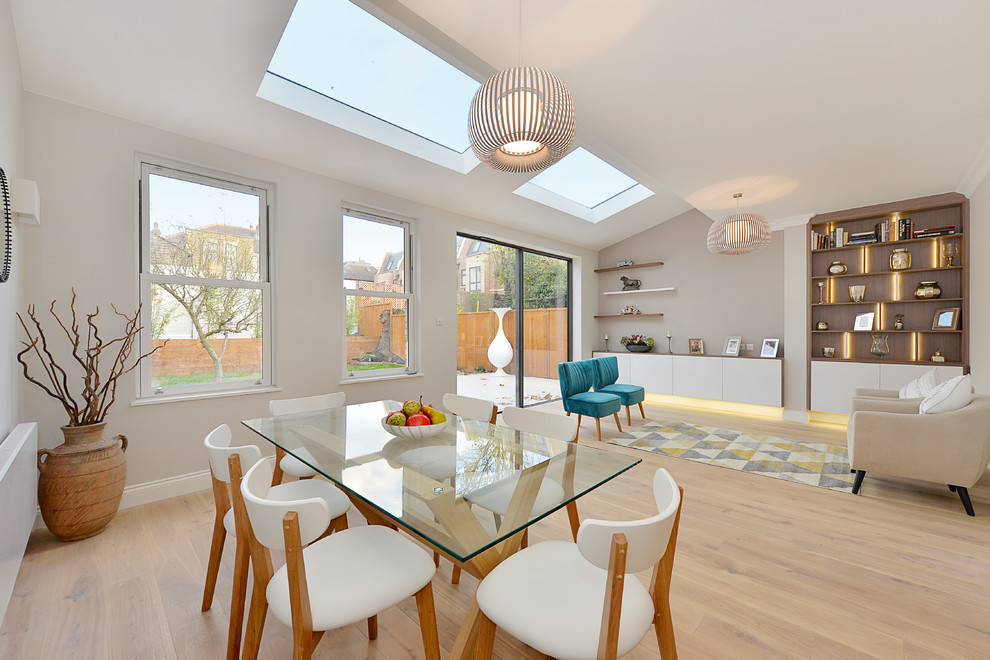 Large contemporary open plan dining room in London with grey walls, light hardwood flooring and brown floors.