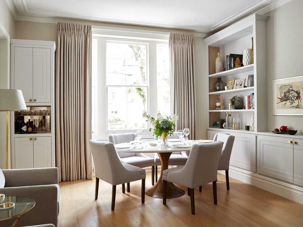 Photo of a traditional enclosed dining room in London with beige walls and light hardwood flooring.