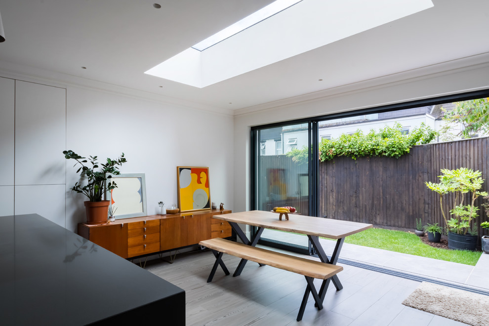 Medium sized contemporary kitchen/dining room in London with light hardwood flooring and grey floors.