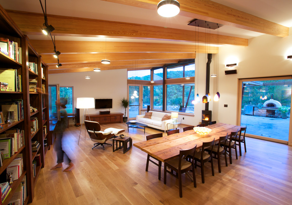 Idee per una sala da pranzo aperta verso il soggiorno design con pareti beige, pavimento in legno massello medio, stufa a legna e cornice del camino in metallo