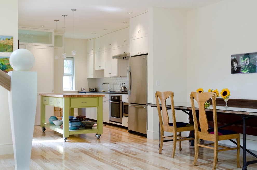 Cette image montre une salle à manger ouverte sur la cuisine traditionnelle de taille moyenne avec un mur blanc, parquet clair, aucune cheminée et un sol marron.