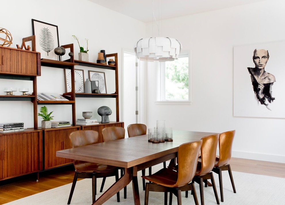 Retro open plan dining room in New York with white walls, medium hardwood flooring and brown floors.