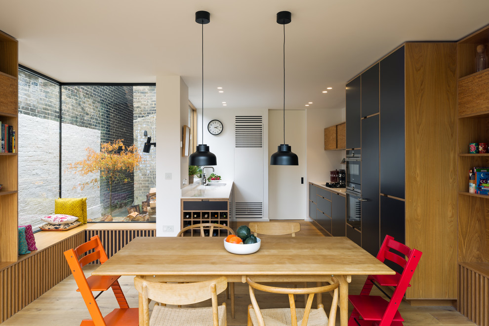 Nordische Wohnküche ohne Kamin mit weißer Wandfarbe, hellem Holzboden und beigem Boden in London