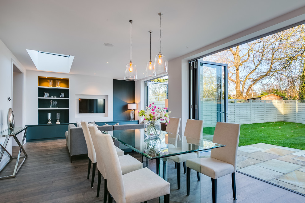 Classic open plan dining room in London with white walls, medium hardwood flooring and brown floors.