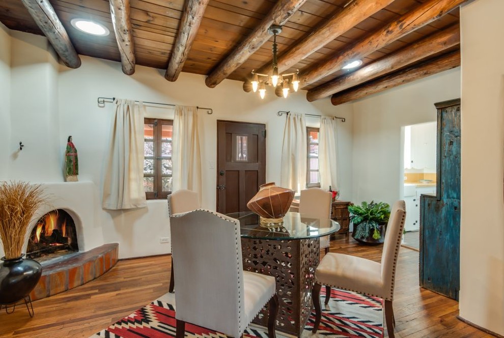 Mid-sized southwest medium tone wood floor and brown floor dining room photo in Albuquerque with beige walls, a corner fireplace and a plaster fireplace