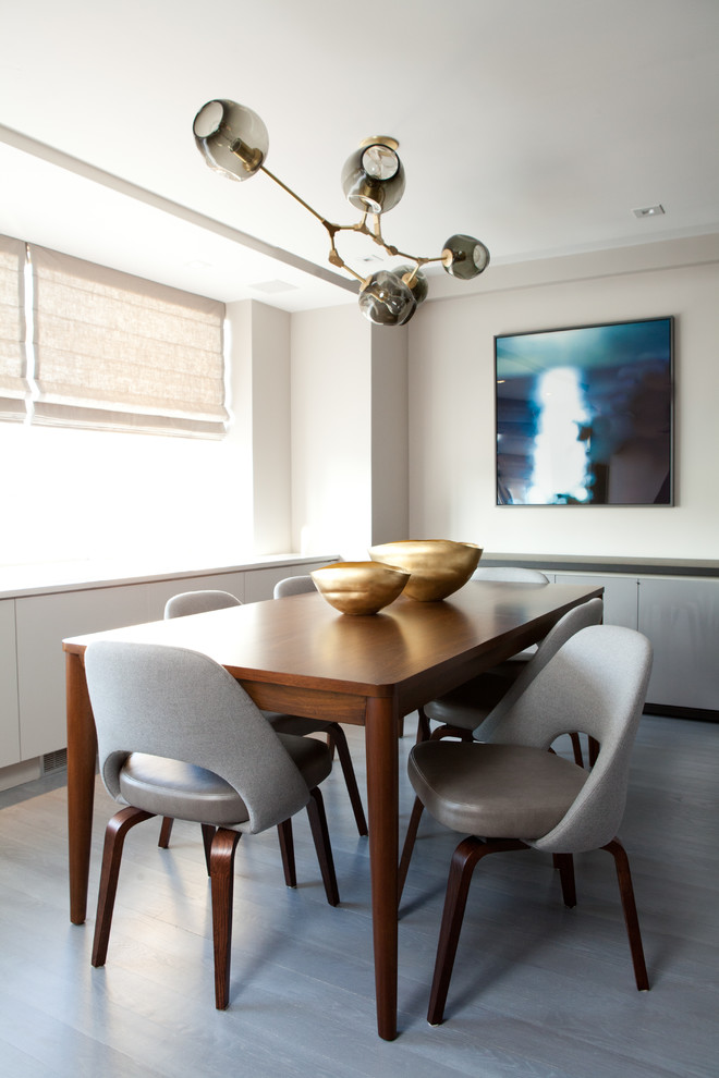 Immagine di una sala da pranzo minimal con pareti bianche, pavimento in legno verniciato e pavimento grigio