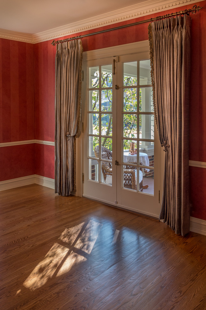 Aménagement d'une grande salle à manger classique fermée avec un mur rouge, un sol en bois brun et aucune cheminée.
