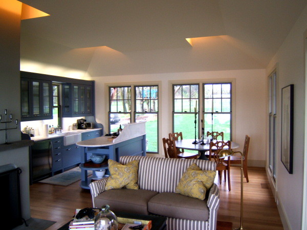 Aménagement d'une salle à manger ouverte sur le salon avec un sol en bois brun, une cheminée double-face et un manteau de cheminée en plâtre.