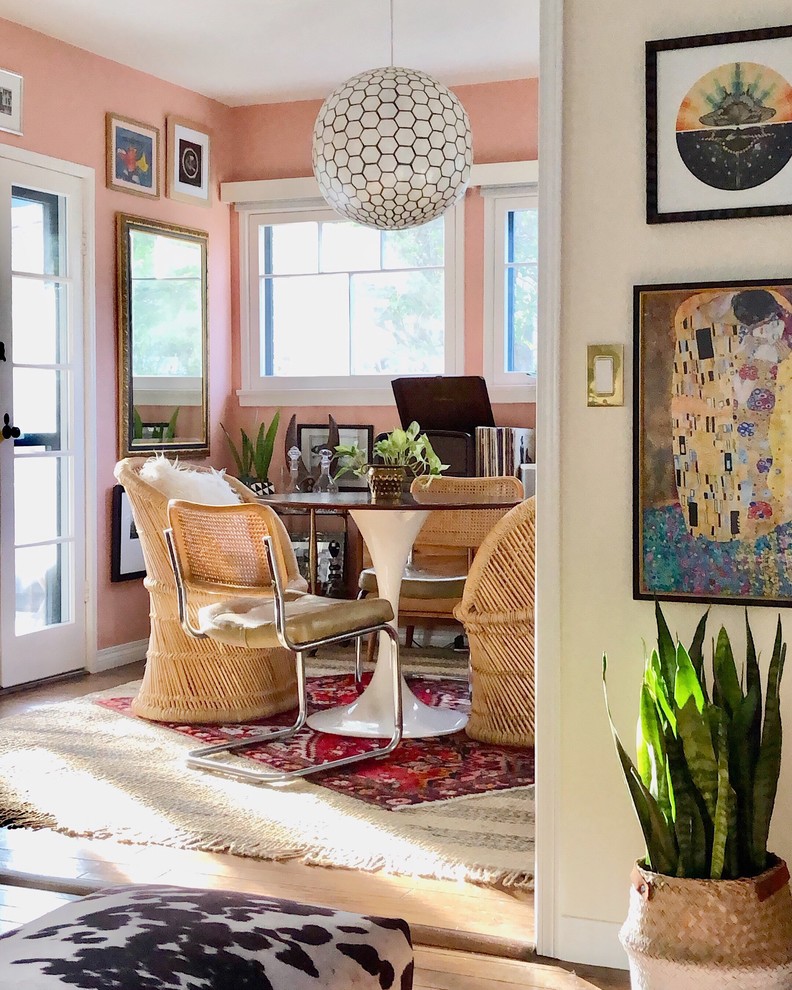 Aménagement d'une salle à manger éclectique avec un mur rose, parquet clair et un sol beige.