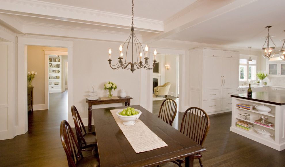 Cette image montre une grande salle à manger ouverte sur la cuisine traditionnelle avec un mur beige et parquet foncé.