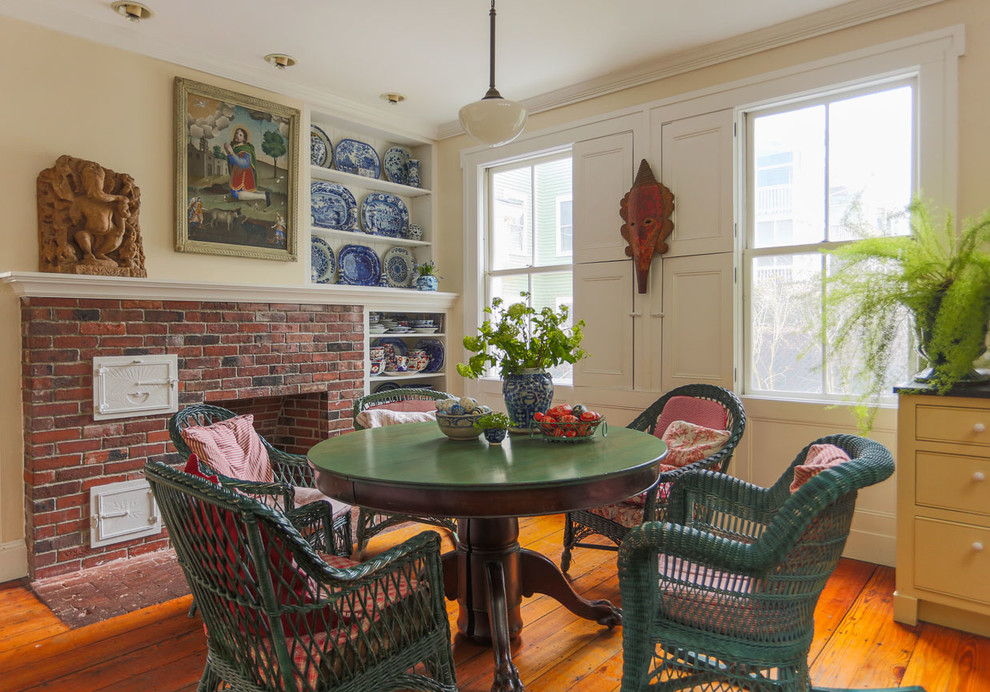 Cette image montre une salle à manger bohème avec un mur beige, un sol en bois brun, une cheminée standard et un manteau de cheminée en brique.