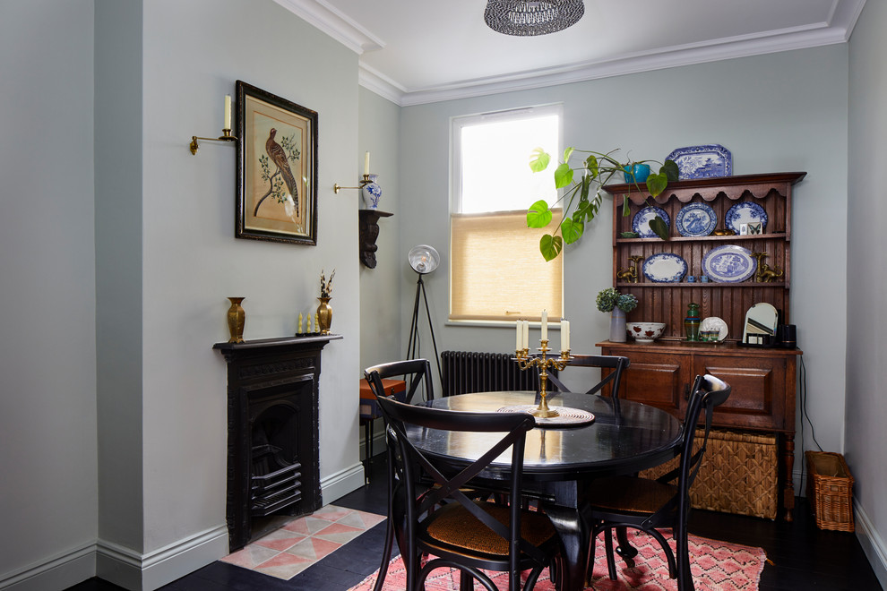 Aménagement d'une salle à manger éclectique avec un mur gris, une cheminée standard et un sol noir.
