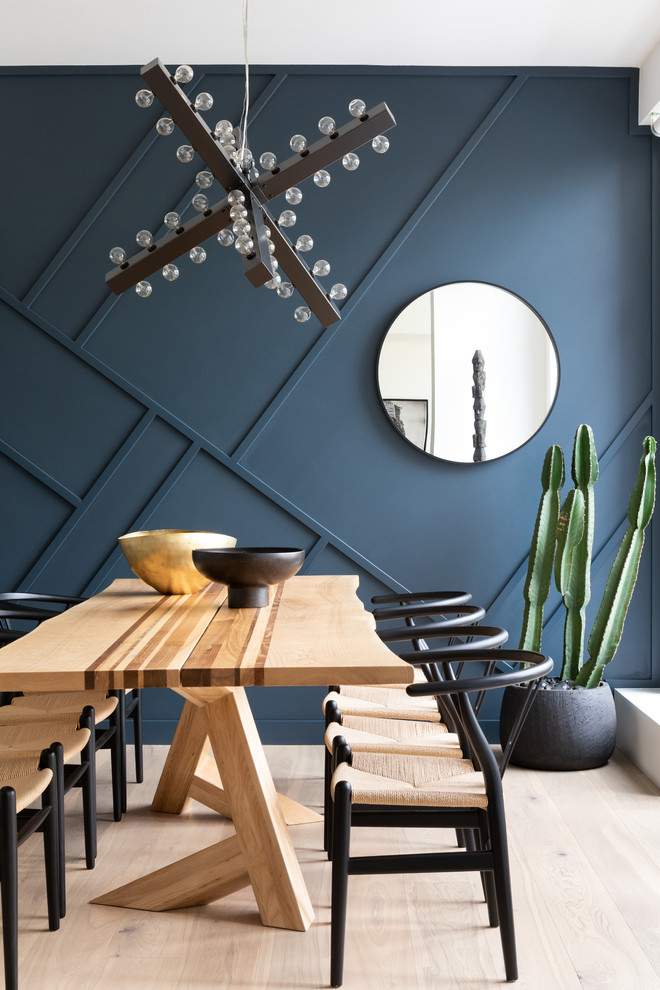 Cette image montre une salle à manger bohème avec un mur bleu, parquet clair, aucune cheminée et un sol beige.