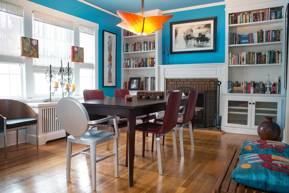 Cette image montre une salle à manger bohème avec un mur bleu, un sol en bois brun, une cheminée standard et un manteau de cheminée en brique.