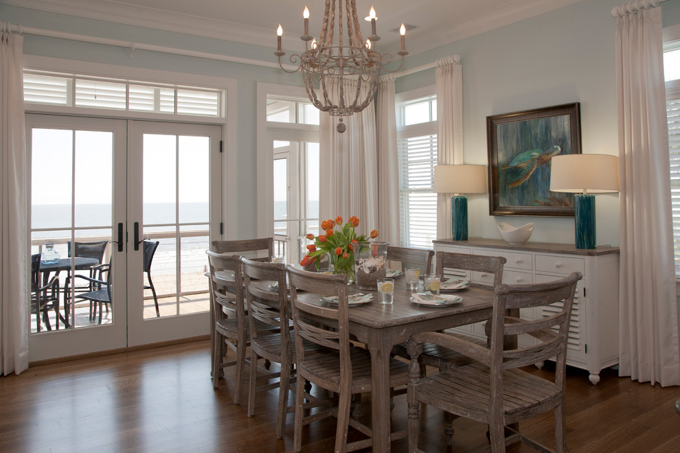 Cette image montre une salle à manger ouverte sur la cuisine marine avec un mur bleu et un sol en bois brun.