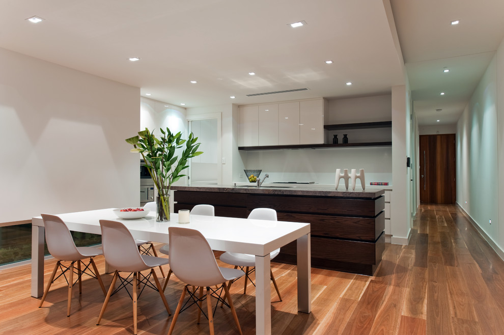 Immagine di una sala da pranzo aperta verso la cucina design di medie dimensioni con pareti bianche e pavimento in legno massello medio