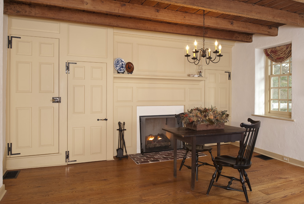 Cette photo montre une salle à manger nature fermée avec un mur blanc, un sol en bois brun, une cheminée standard et un manteau de cheminée en plâtre.