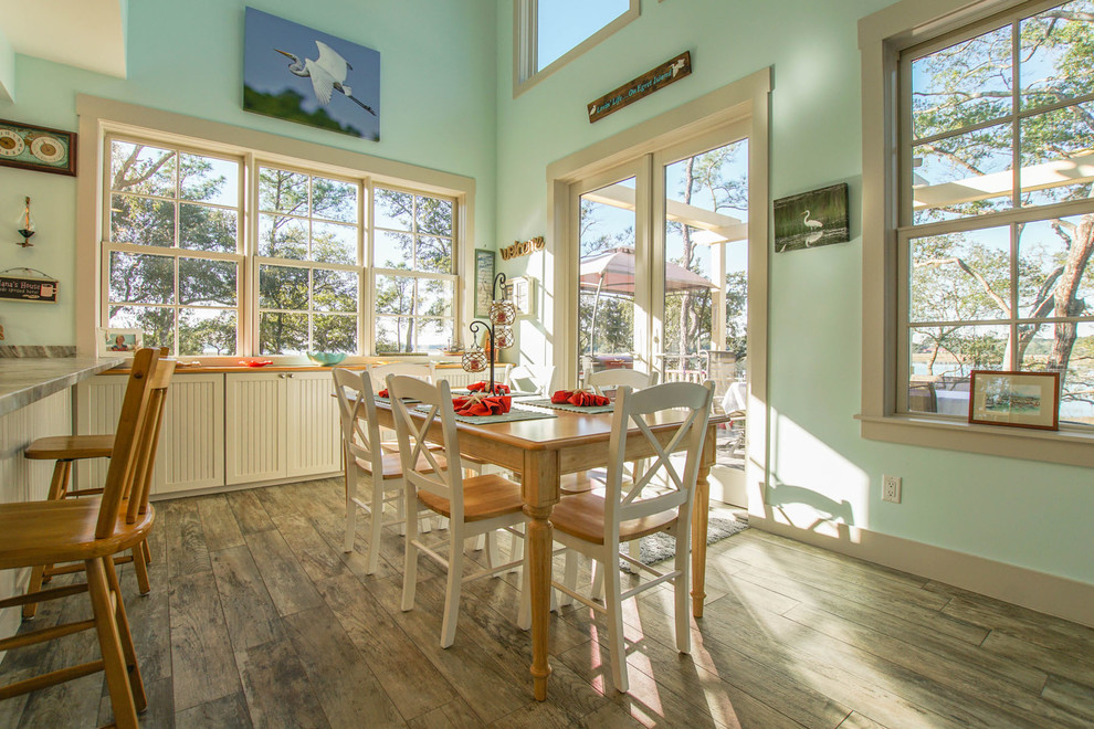 Cette image montre une salle à manger ouverte sur le salon marine de taille moyenne avec un mur bleu, un sol en bois brun et aucune cheminée.