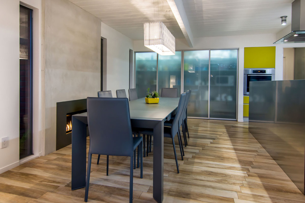 На фото: кухня-столовая среднего размера в стиле ретро с белыми стенами, полом из керамогранита, стандартным камином и фасадом камина из бетона