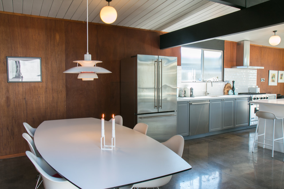 На фото: кухня-столовая среднего размера в стиле ретро с коричневыми стенами и бетонным полом с