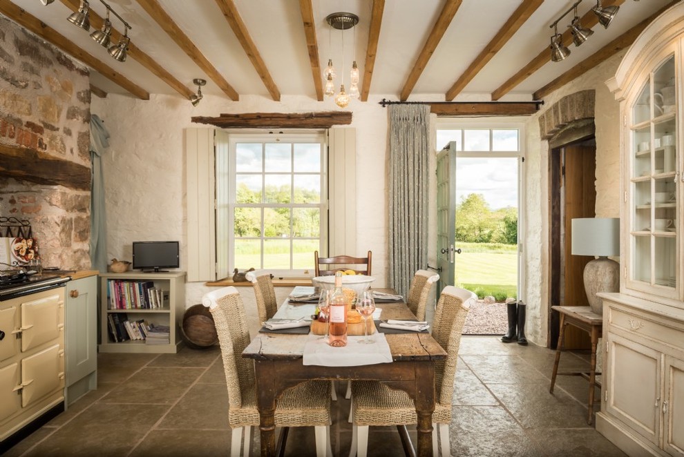 Immagine di una sala da pranzo aperta verso la cucina rustica di medie dimensioni con pavimento in pietra calcarea, pavimento beige e pareti bianche