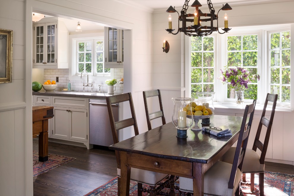 Inspiration pour une salle à manger ouverte sur la cuisine traditionnelle de taille moyenne avec parquet foncé et un mur blanc.