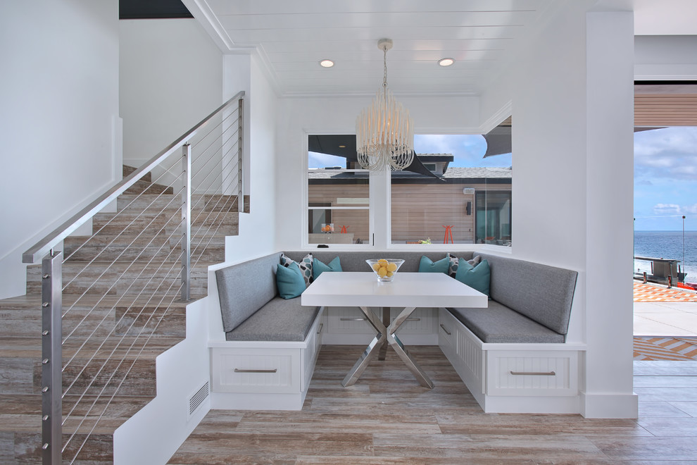 Foto di una sala da pranzo aperta verso la cucina costiera con pareti bianche e pavimento in legno massello medio