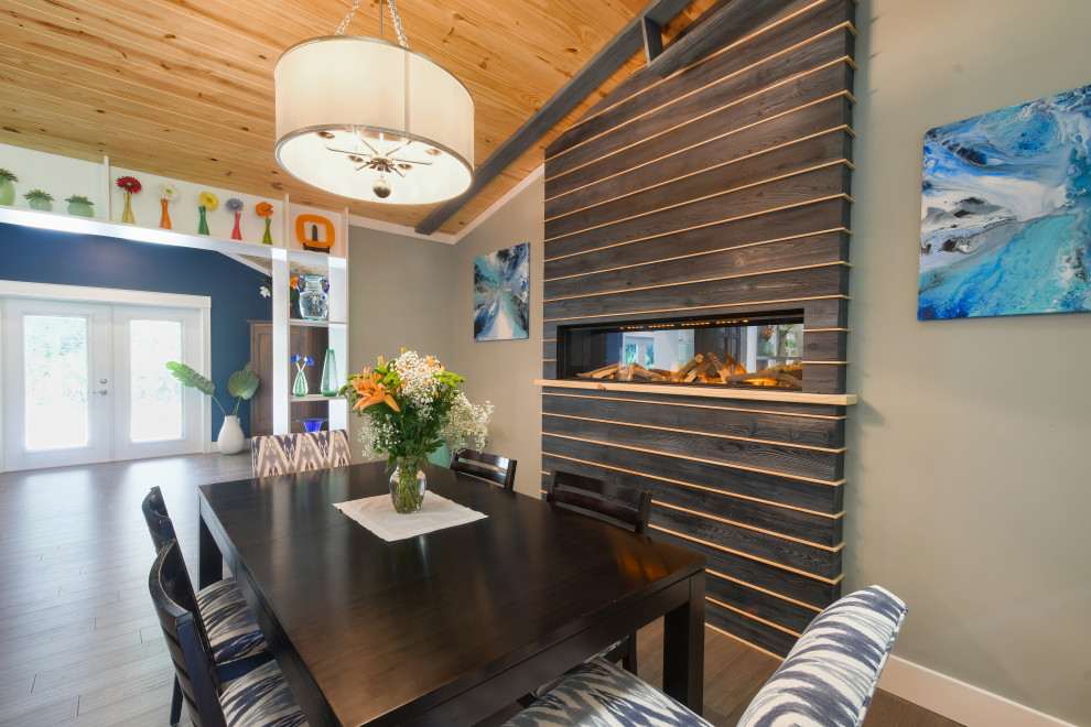 Exemple d'une salle à manger ouverte sur la cuisine éclectique de taille moyenne avec un mur vert, parquet en bambou, cheminée suspendue, un manteau de cheminée en bois et un sol marron.