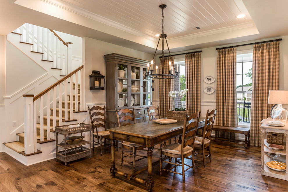 Immagine di una sala da pranzo aperta verso il soggiorno country con pareti beige, pavimento in legno massello medio e pavimento marrone