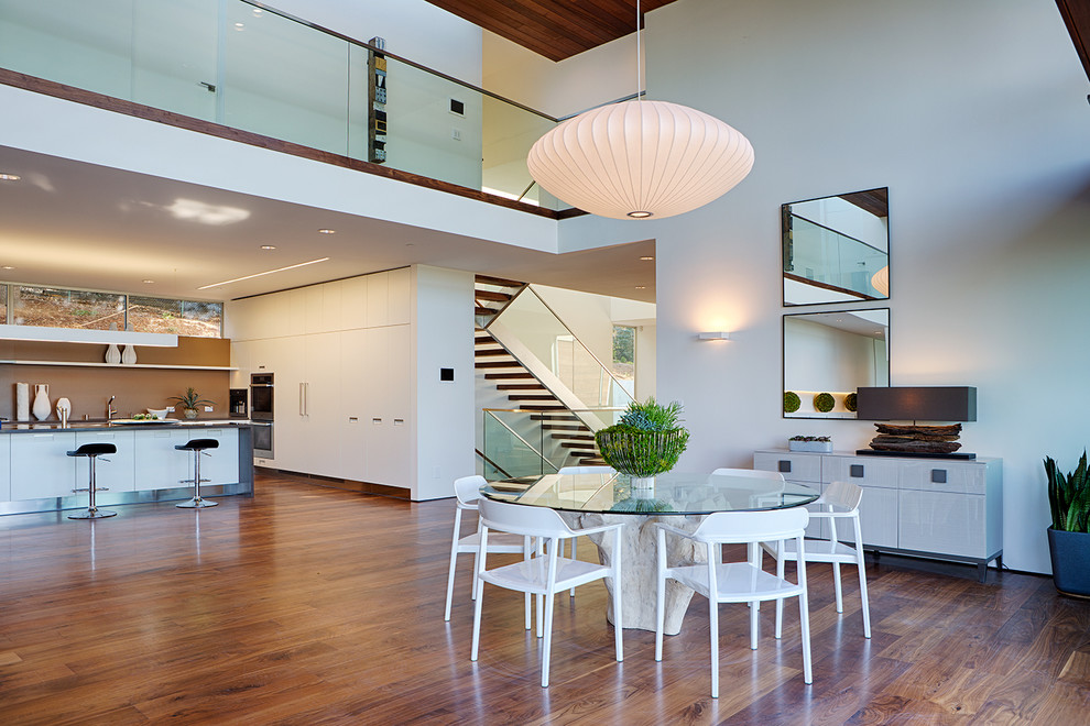 Große Moderne Wohnküche ohne Kamin mit weißer Wandfarbe und braunem Holzboden in Houston