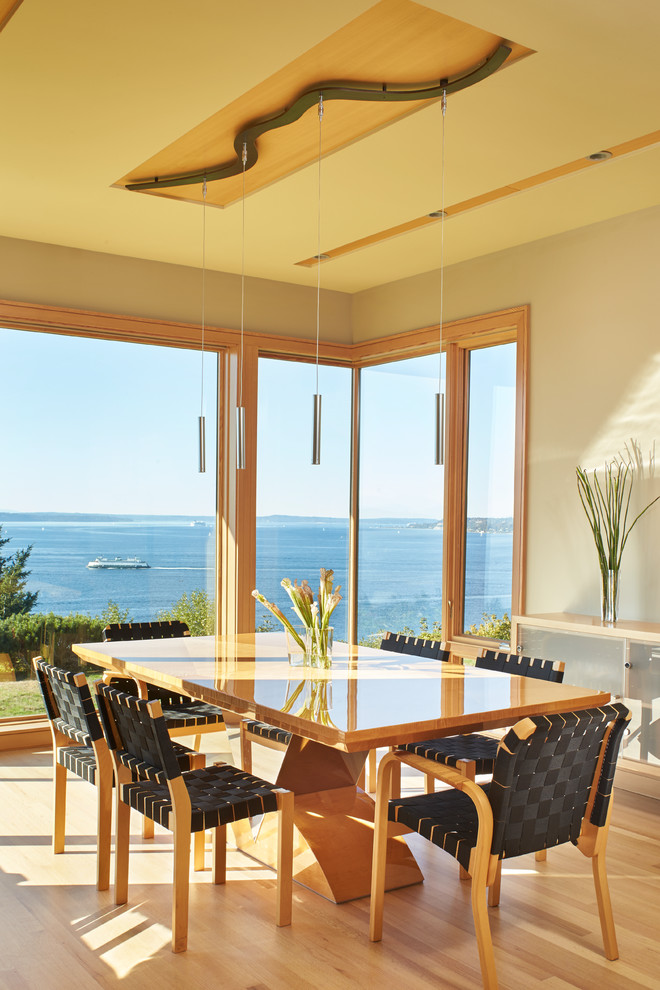 Cette image montre une salle à manger ouverte sur la cuisine design de taille moyenne avec un mur beige et un sol en bois brun.