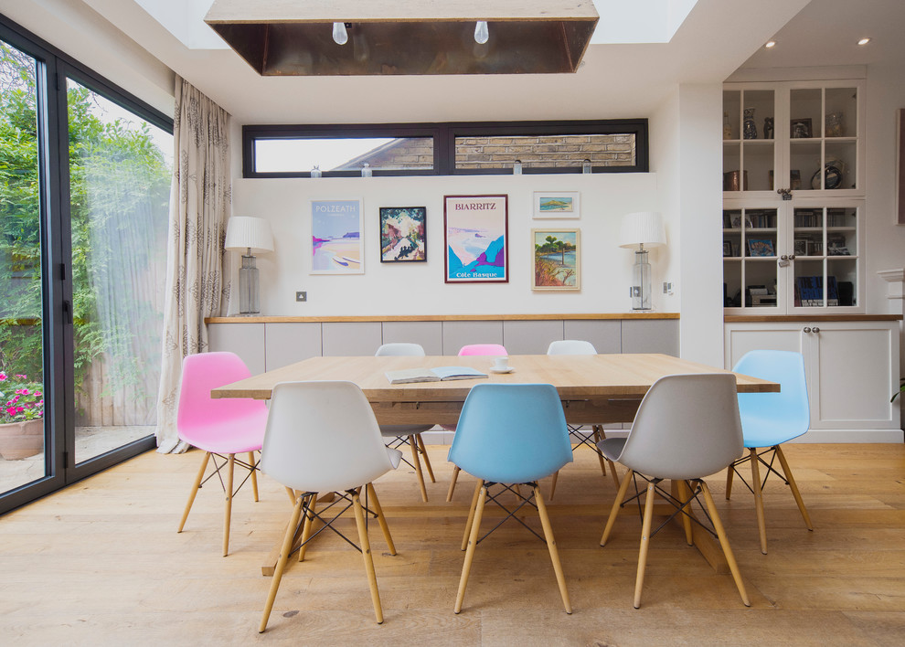Foto di una sala da pranzo aperta verso la cucina nordica con pareti bianche, parquet chiaro e pavimento beige