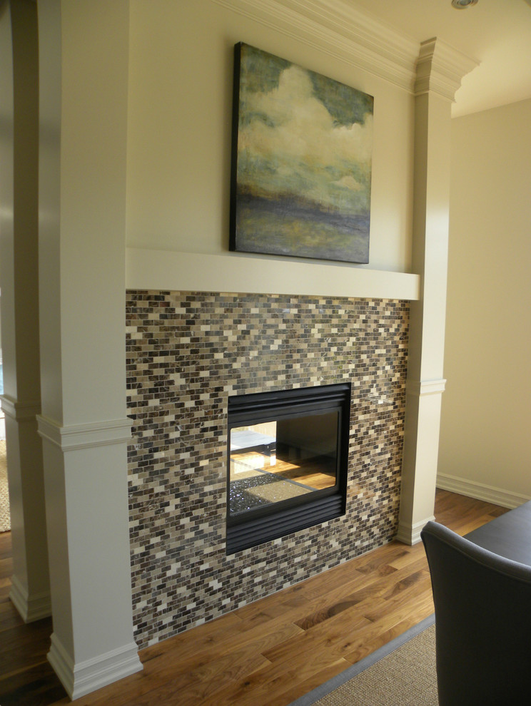 Example of a transitional medium tone wood floor dining room design in Calgary with beige walls, a two-sided fireplace and a tile fireplace