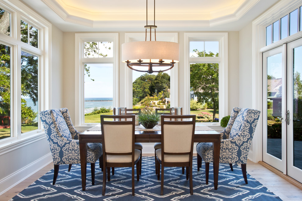 Immagine di una grande sala da pranzo aperta verso il soggiorno stile marino con pareti beige e parquet chiaro