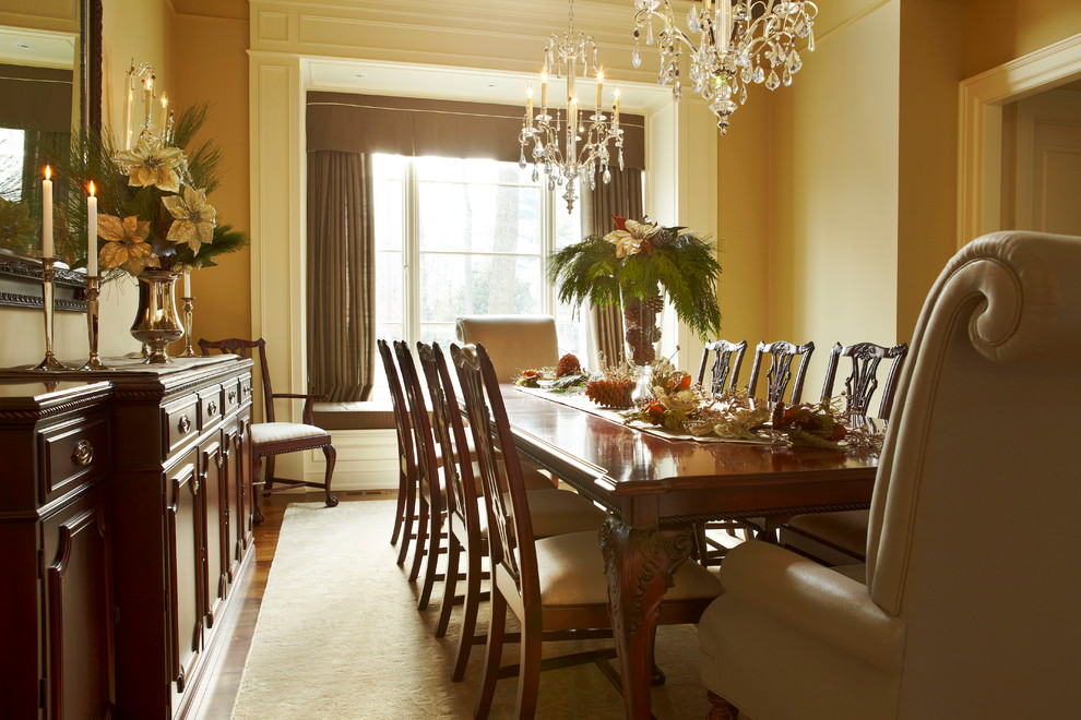 Immagine di una grande sala da pranzo classica chiusa con pareti beige e pavimento in legno massello medio