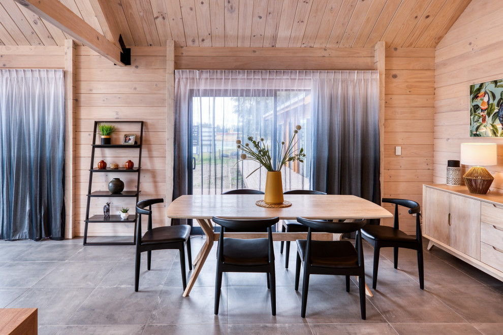 Exemple d'une salle à manger ouverte sur le salon scandinave en bois avec un mur marron, sol en béton ciré, aucune cheminée, un sol gris et poutres apparentes.