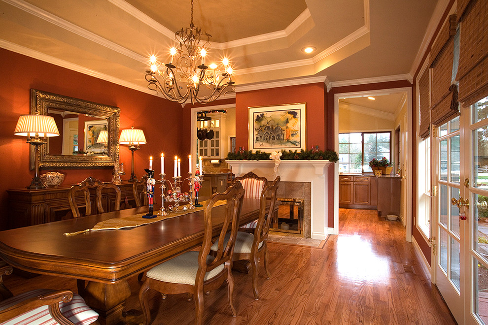 Foto di una grande sala da pranzo tradizionale chiusa con pareti rosse, pavimento in legno massello medio, camino bifacciale, cornice del camino in pietra e pavimento marrone